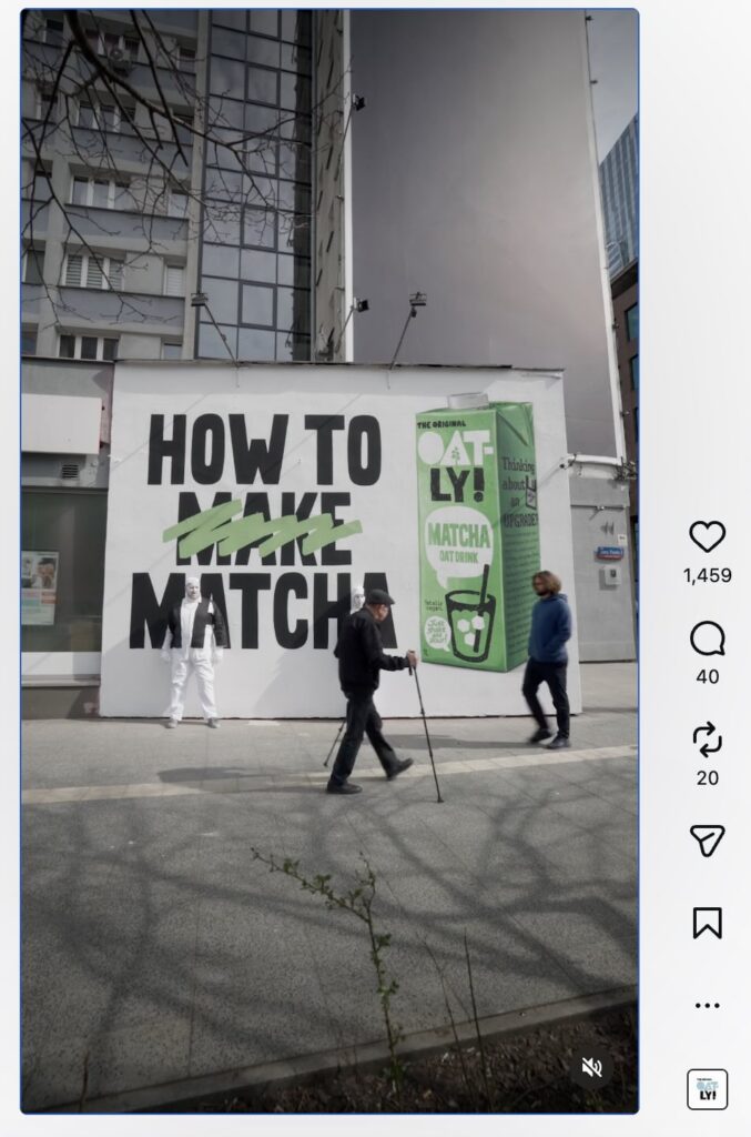 An Instagram Reel from Oatly about their new matcha offering. In the video, two people are dressed to camouflage with an Oatly billboard and are surprising people on the street by handing them matcha beverages.