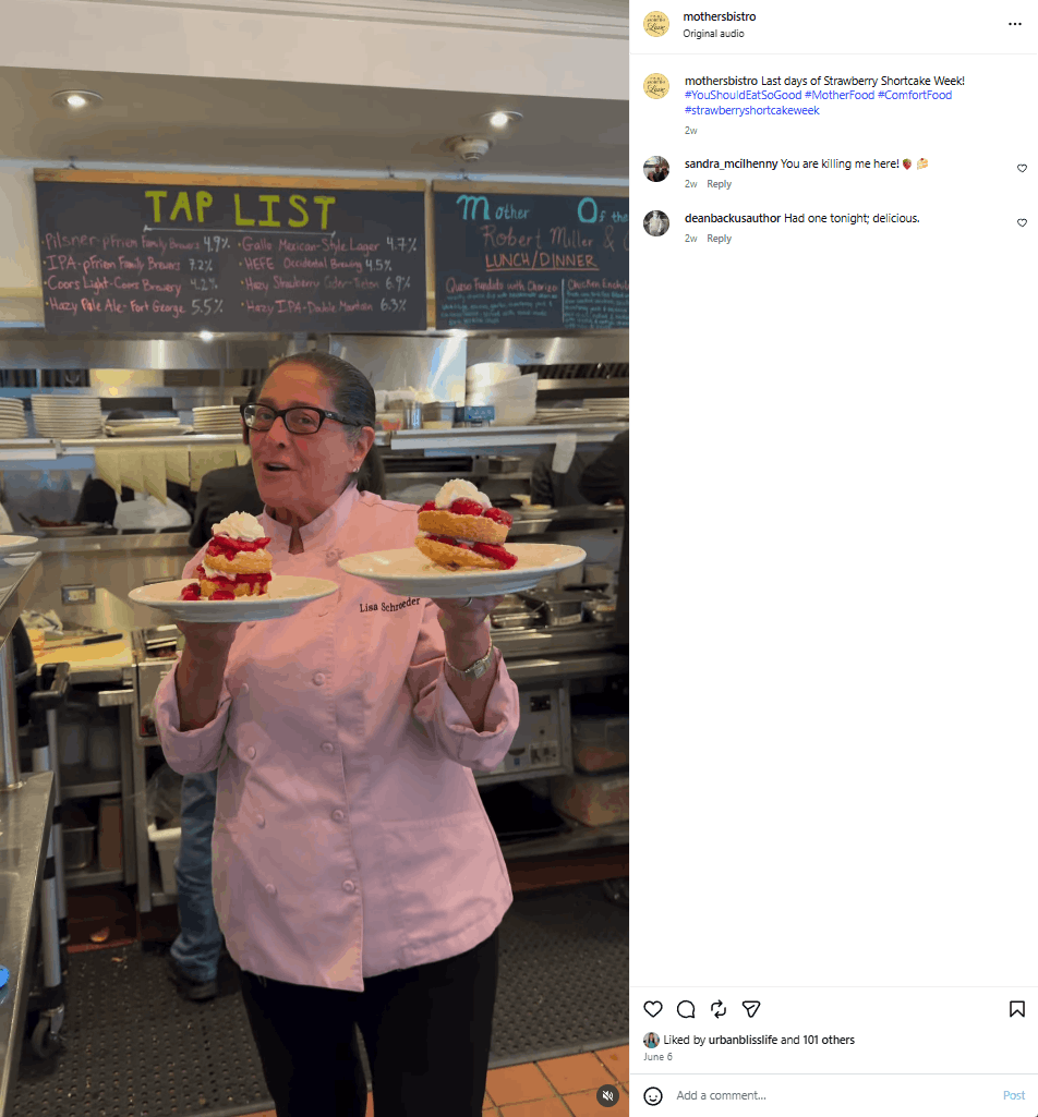 Chef Lisa Schroeder holds up two plates of strawberry shortcake in her kitchen at Mother’s Bistro. She wears a pink chef’s jacket. The video is posted to the restaurant’s Instagram page. 