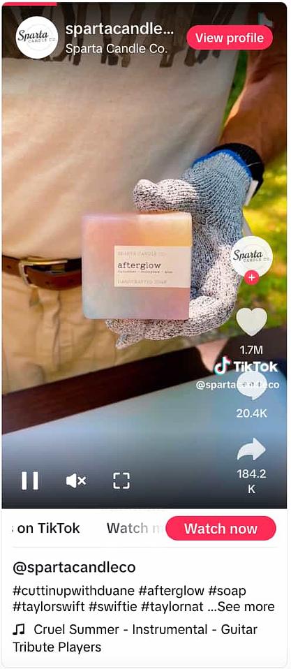 TikTok video from Sparta Candle Co. showing a gloved hand holding a multi-colored soap named Afterglow 